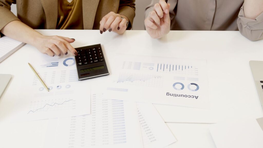 Two professionals reviewing financial documents with a calculator