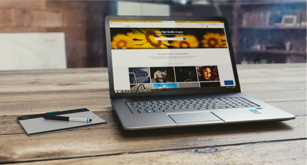 Laptop showing an open webpage on a desk with a tablet and pen