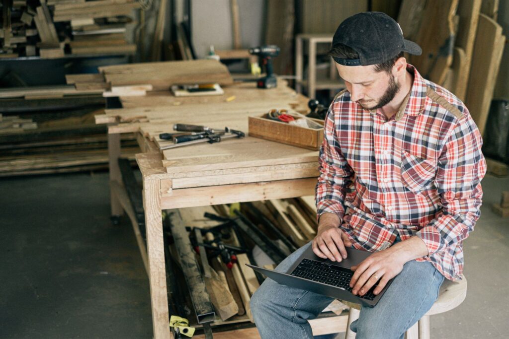 Carpenter working on a laptop in a wood workshop