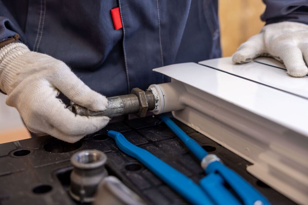 Plumber installing a radiator pipe with specialized tools